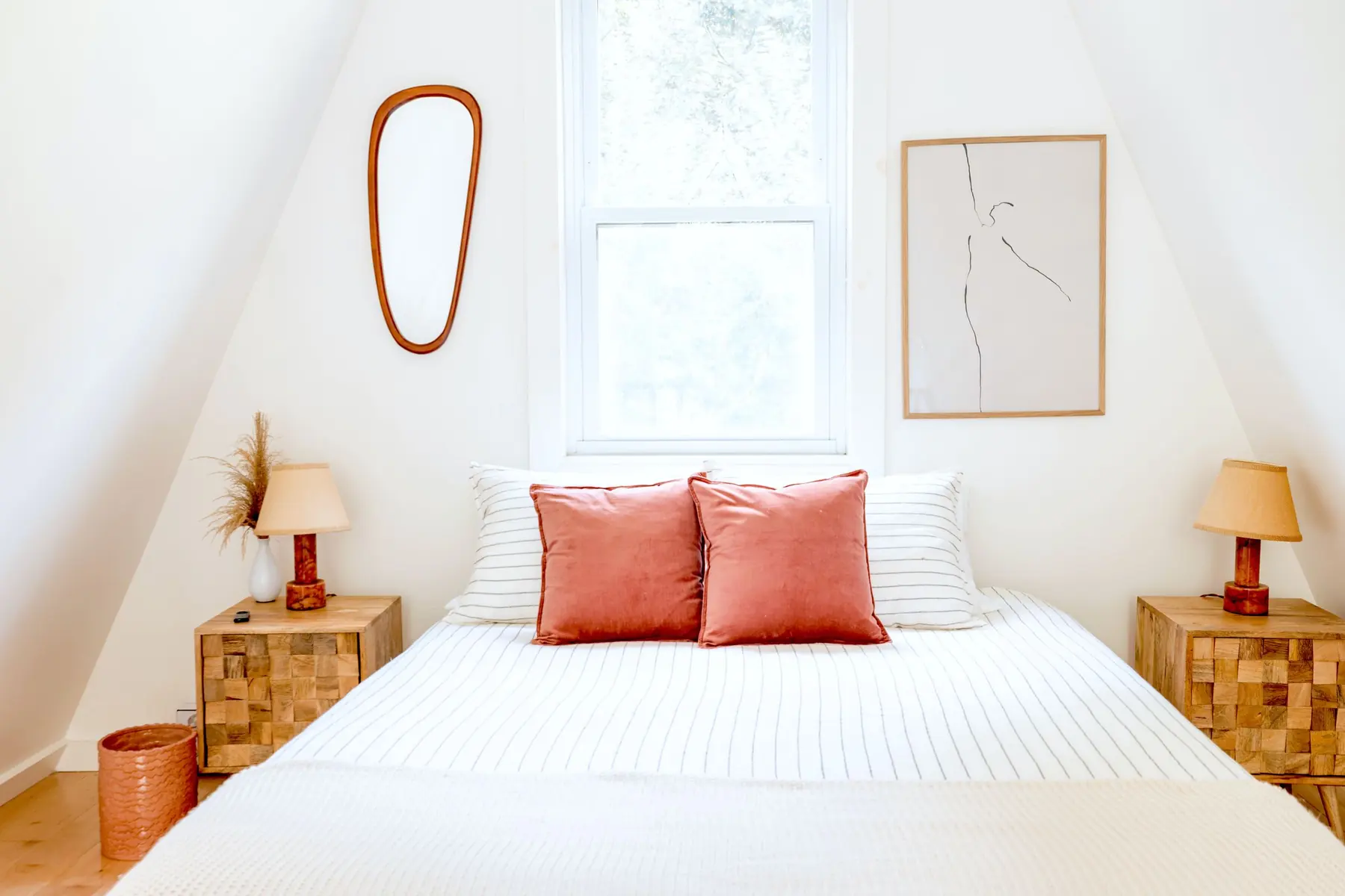 Chambre mansardée, lit blanc, coussins terracotta et lampes de chevet