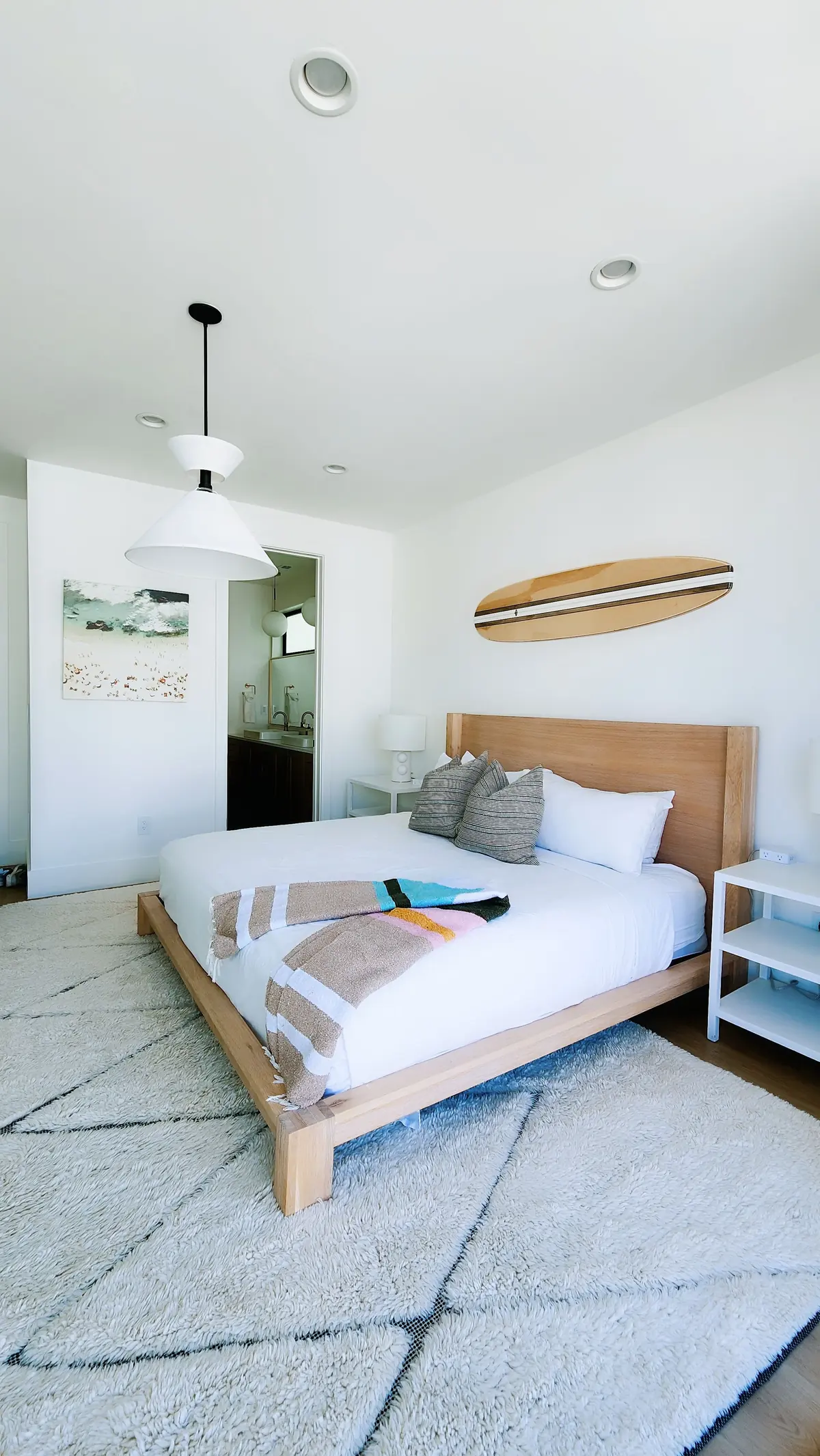 Chambre claire, lit en bois et planche de surf accrochée au mur
