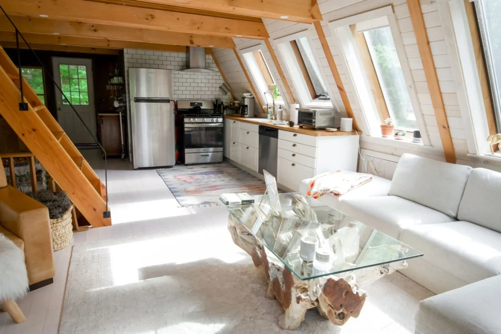Cabane Itsaso : séjour sous charpente en bois, canapé blanc et cuisine ouverte