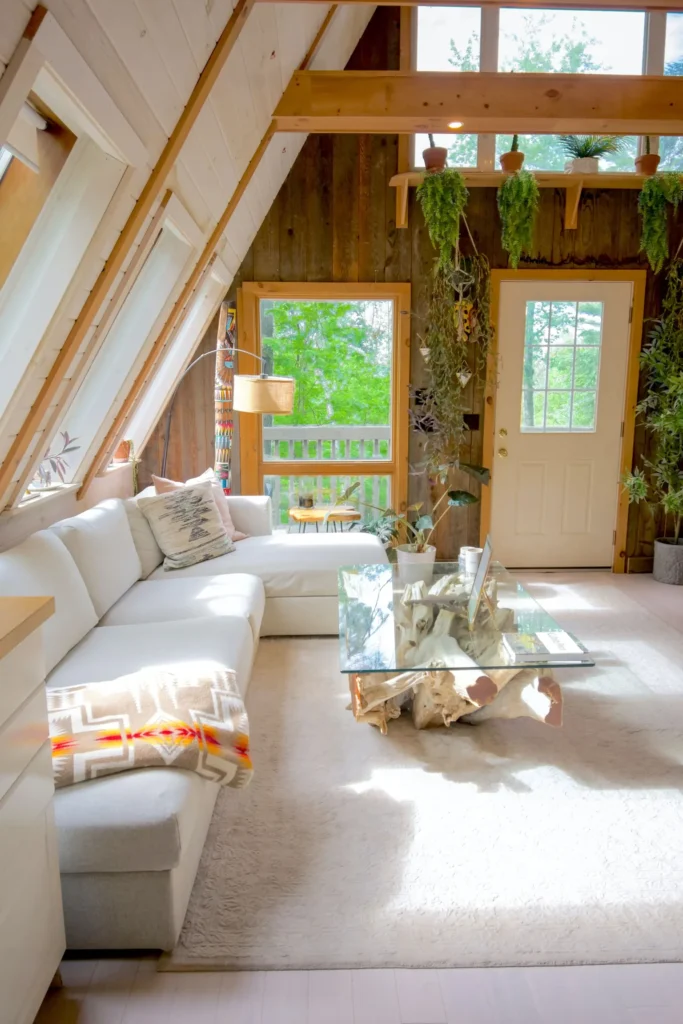 Cabane Itsaso : séjour sous la charpente, canapé blanc et porte du jardin