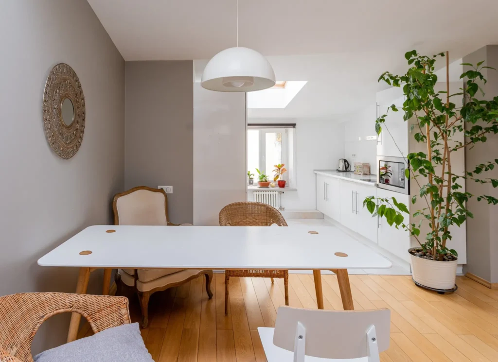 Loft des Halles : pièce de vie lumineuse, table blanche, chaises cannées et cuisine ouverte