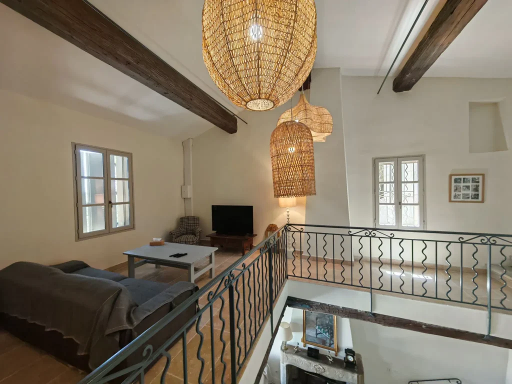 Maison Lur : séjour sous poutres, suspensions en rotin et mezzanine