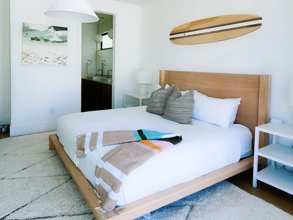 Studio Surf : coin nuit, lit en bois et planche de surf accrochée au mur